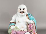 une image représentant une figurine de Bouddha riant, assis sur un coussin