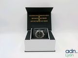 une image représentant une montre dans un écrin noir posé sur une surface blanche