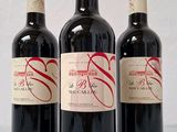 trois bouteilles de vin rouge sont alignées sur une table