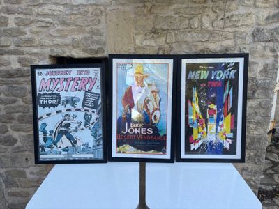 three framed movie posters on a table in front of a stone wall
