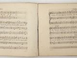 an open book with music notes on it sitting on a table