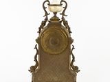 a large antique clock with a glass vase on top of it