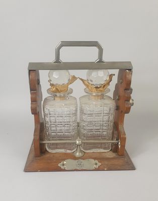 paire de carafes en verre posées sur un socle en bois, sur fond blanc