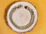 gold chain bracelet on a wood slice on a yellow background