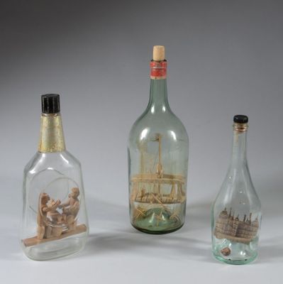 three glass bottles with a ship in them on a white surface
