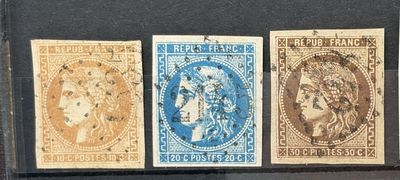 Quatre timbres de couleurs différentes sont exposés dans une vitrine.