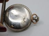 a silver pocket watch being held by a person with a pair of scissors