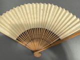 a wooden fan on the wall with a gray background