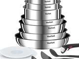 une pile de casseroles et de poêles en inox à côté d'un couteau et d'une fourchette