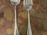 two silver spoons and a fork on a table