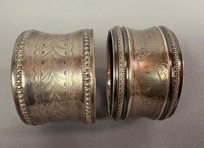 une paire de bracelets en argent ornés de motifs gravés, posés sur une table