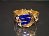 gold bracelet with lapis and diamonds on a black surface