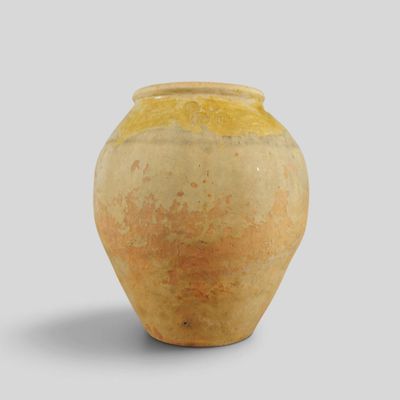 a yellow vase sitting on a white surface with a gray background