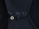 the back of a black jacket with buttons on it