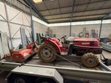 un tracteur rouge sur une remorque dans un entrepôt