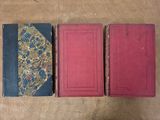 three old books sitting on top of a table next to each other
