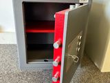 a metal safe box with a red door on the floor