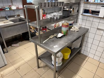 a kitchen with a large metal table and a lot of dishes on it