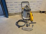 Une image représentant un aspirateur est posée sur le sol, à côté d'un tuyau