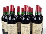 six bottles of red wine lined up in a row on a white surface