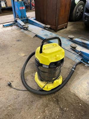a yellow vacuum sitting on the ground next to a blue car