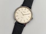 gros plan d'une montre sur une surface blanche avec un bracelet noir