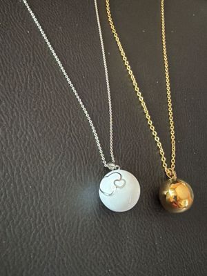 two gold and silver necklaces on a black surface