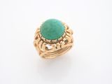 gros plan d'une bague en or avec une pierre verte
