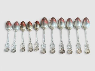 six cuillères en argent sont alignées sur une surface blanche