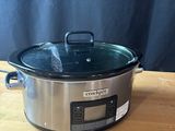 a crock pot sitting on a wooden table with a blue curtain in the background