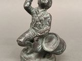 une statue représentant un homme assis sur un tonneau