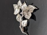 une broche en argent ornée de fleurs sur un fond noir
