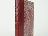 un vieux livre à la couverture rouge posé sur une surface blanche
