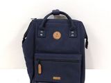 navy blue backpack with leather handles and zippers sitting on a white surface