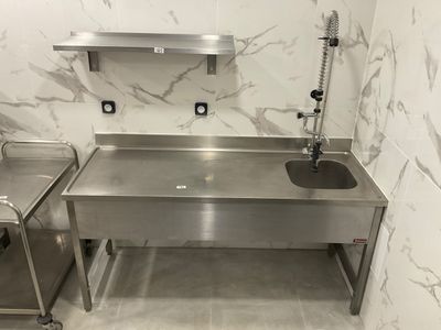 a stainless steel sink in the corner of a bathroom