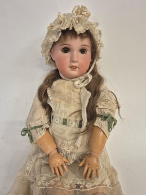 an antique doll with a bonnet and dress sitting on a white surface
