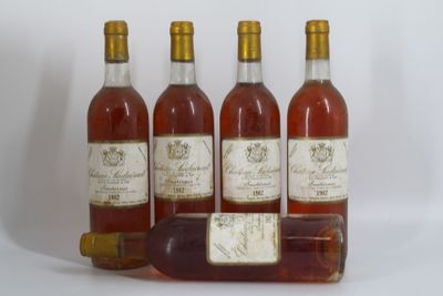 quatre bouteilles de vin posées les unes à côté des autres sur une surface blanche