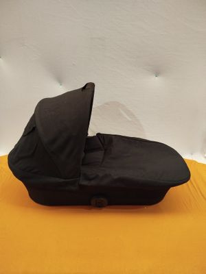 une poussette noire vide posée sur une surface jaune, sur fond blanc