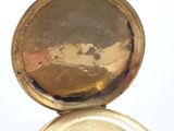 a gold pocket watch sitting on top of a white surface