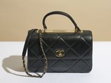 un sac Chanel noir avec des finitions dorées posé sur une table blanche