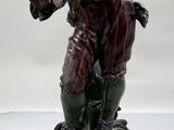 statue représentant un homme tenant un oiseau, posée sur un socle en bois