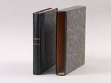 an open book with a black cover sitting on top of a white surface