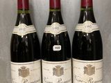trois bouteilles de vin sont alignées sur une table en verre