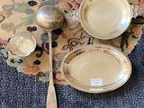 three silver dishes and spoons on a rug