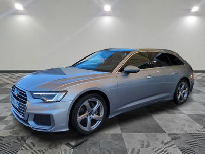 Une Audi argentée est garée dans une grande pièce au sol carrelé.
