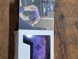 packaging of a purple game controller sitting on a wooden table
