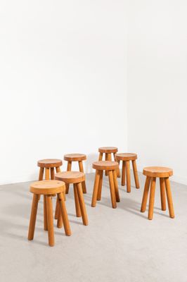 six tabourets en bois dans une pièce aux murs blancs