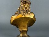 bronze bust of a man with long hair on a pedestal