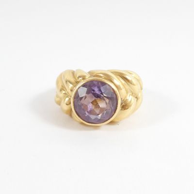 a close up of a gold ring with a purple stone