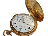 a gold pocket watch sitting on a white surface